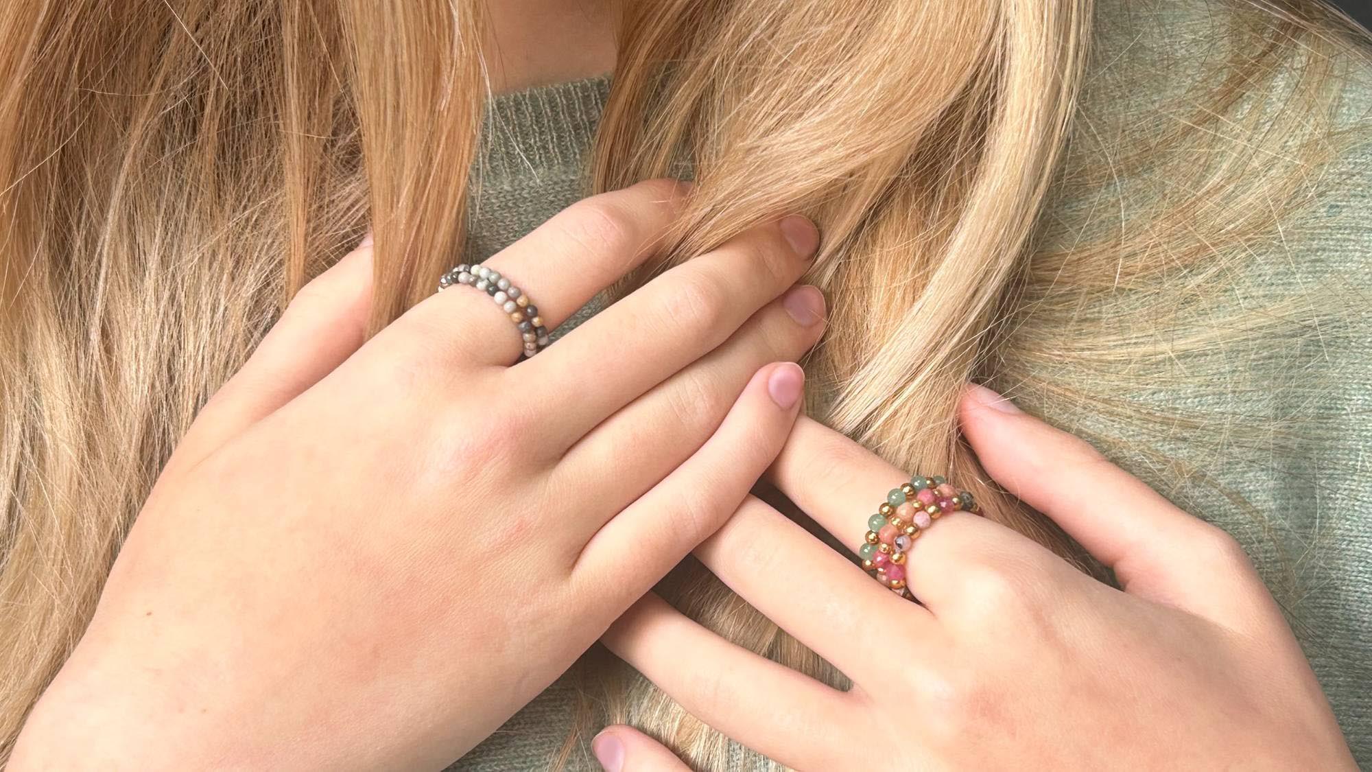 Hand wearing Leopoldine's Celestine Green Aventurine and pink Rhodonite rings and Aurora Natural Grey Picasso rings, showcasing gemstone jewellery