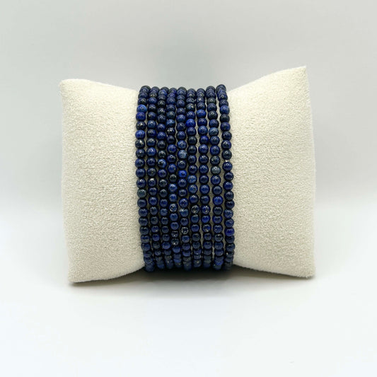 Lapis lazuli stacking bracelet set featuring multiple rows of deep blue gemstone beads on a neutral cushion – elegant and timeless arm candy.