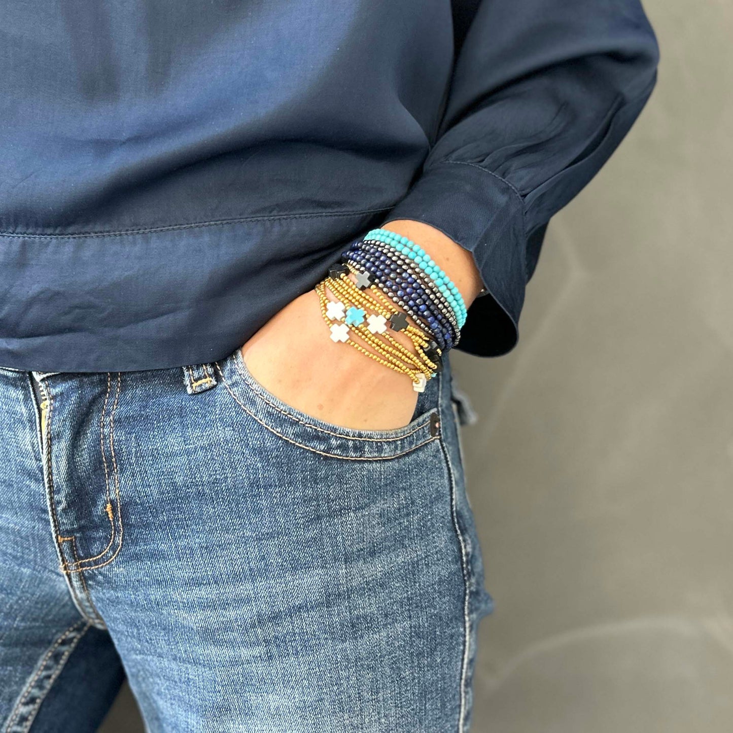 Stack of stretch Aurora bracelets in lapis lazuli, turquoise and hematite, paired with adjustable Divine bracelets in white, turquoise and black – colourful, affordable layered jewellery