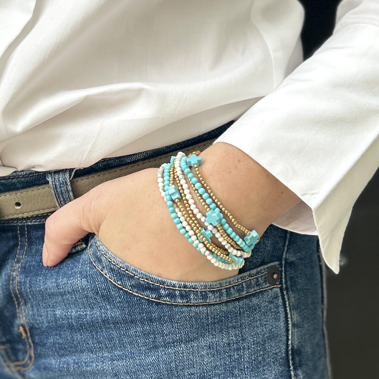 Wrist adorned with stackable Calypso turquoise and gold beaded bracelets – playful affordable jewellery, lightweight and perfect for layering.