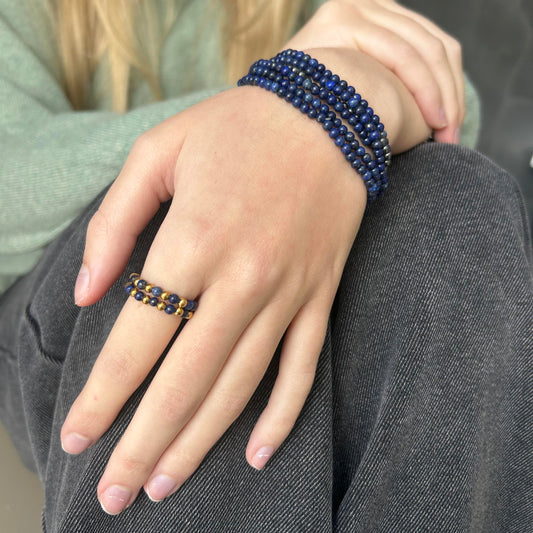 Stacked lapis lazuli ring and matching beaded bracelets styled on hand with soft knit and denim contrast.