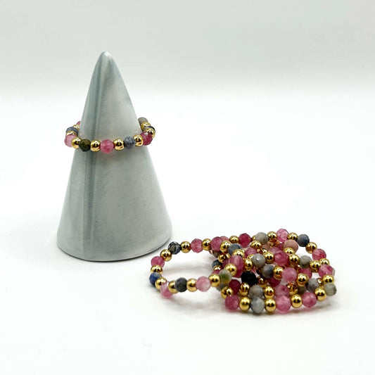 Leopoldine Celestine ring in pink rhodonite and stainless steel gold beads – delicate elastic stacking ring set, displayed on cone stand with modern minimal touch