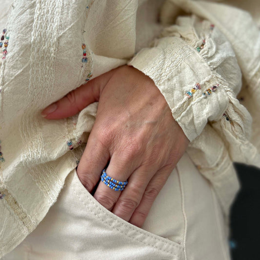Trio of blue glass bead rings with gold accents from Leopoldine, stacked on finger — vibrant and stylish UK jewellery set with playful charm.