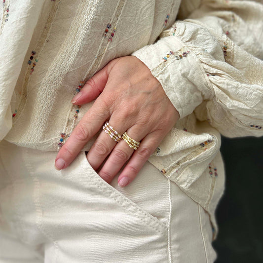 Close-up of affordable Confettis rings by Leopoldine, set of 3 with pink and cream glass beads and gold accents, UK stackable style.