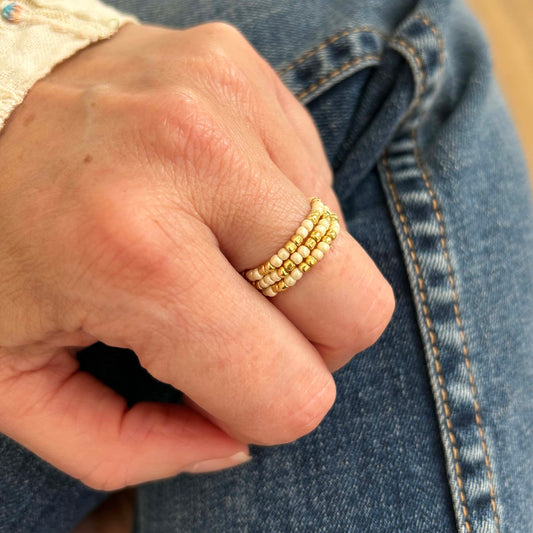 Close-up of stackable ivory glass bead rings with golden accents. Delicate and affordable jewellery for everyday wear – stylish, elegant and budget-friendly.