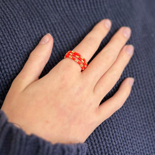 Close-up of hand wearing Leopoldine Confettis red glass beaded rings with gold details — playful stackable jewellery made to pop with every outfit.
