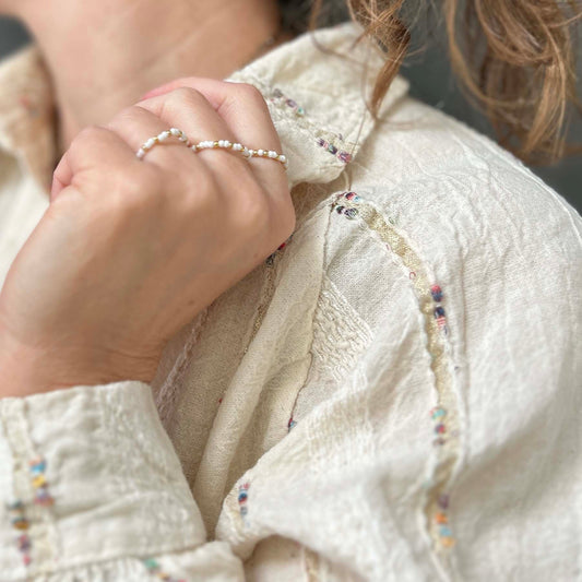 Affordable Confettis ring trio by Leopoldine, featuring white glass beads and gold accents, worn for a minimalist stacking look.