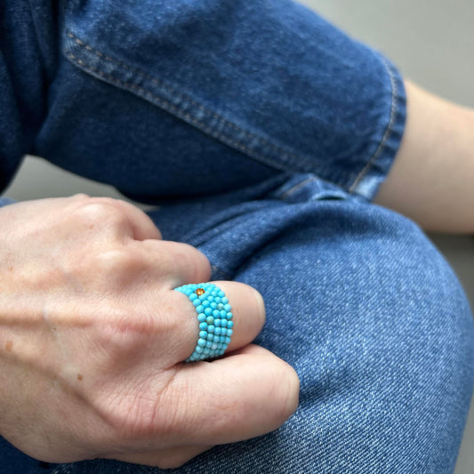Stacked turquoise rings pop against denim, adding a cheerful twist to a relaxed everyday look – colourful rings UK.