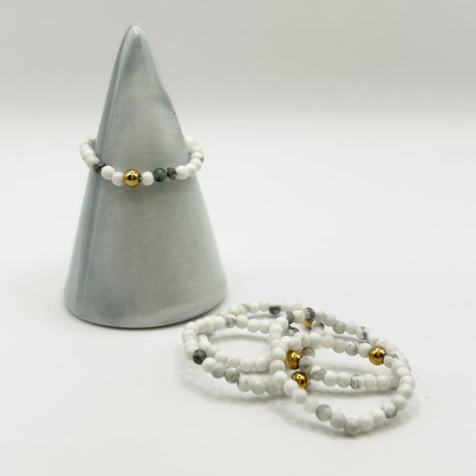 Affordable white turquoise ring with gold accent displayed on a ceramic cone, with matching stackable gemstone rings – dainty jewellery UK.