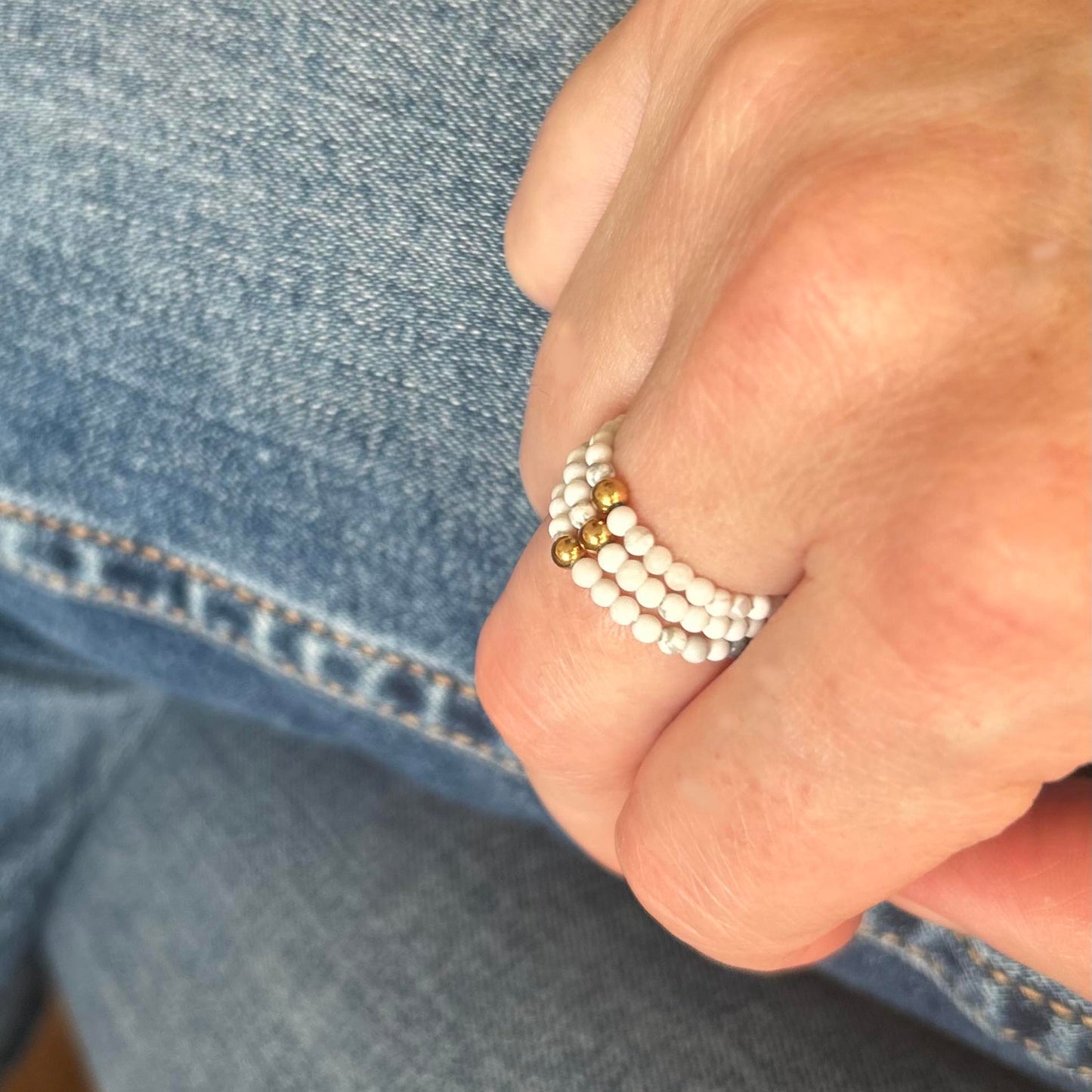 Elegant stack of gold and silver rings with cubic zirconia on hand wearing denim jeans