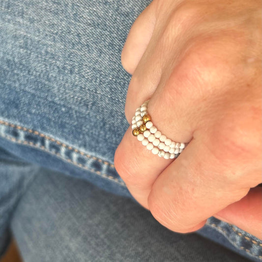 Elegant stack of gold and silver rings with cubic zirconia on hand wearing denim jeans