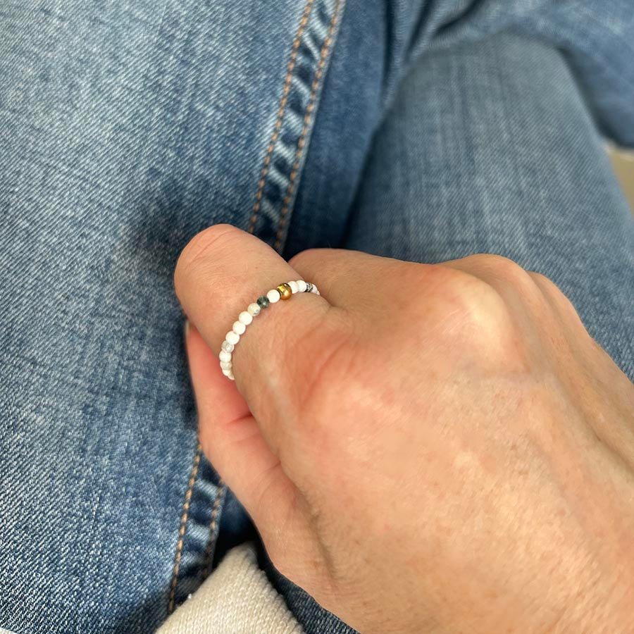Affordable white turquoise beaded ring worn on thumb, styled casually with denim – dainty UK stackable jewellery.