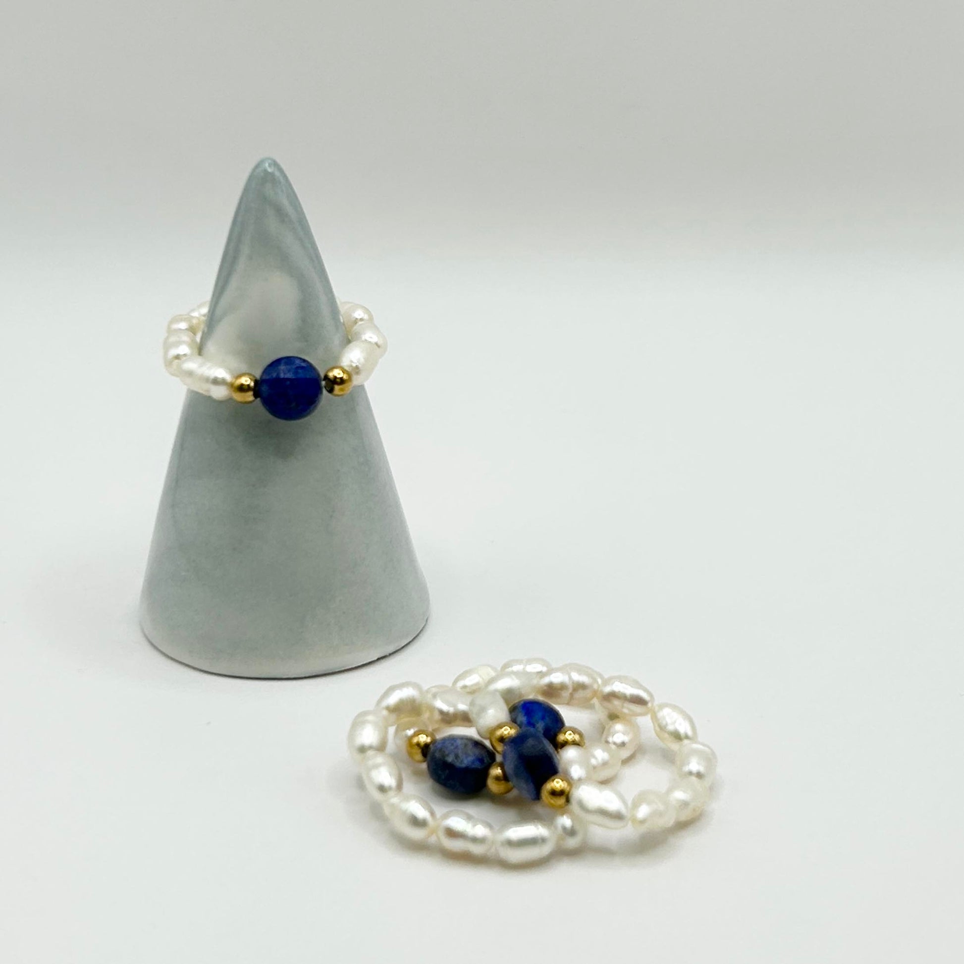 Affordable Leopoldine Amity ring with deep blue lapis lazuli and pearl-style beads, styled on soft display cone – elegant stackable jewellery under £15 UK.