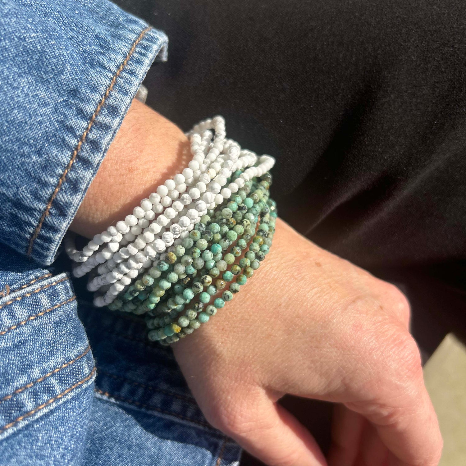 Affordable beaded gemstone bracelets in white and green tones, stacked on wrist with casual denim jacket – boho-chic style for everyday fashion lovers.
