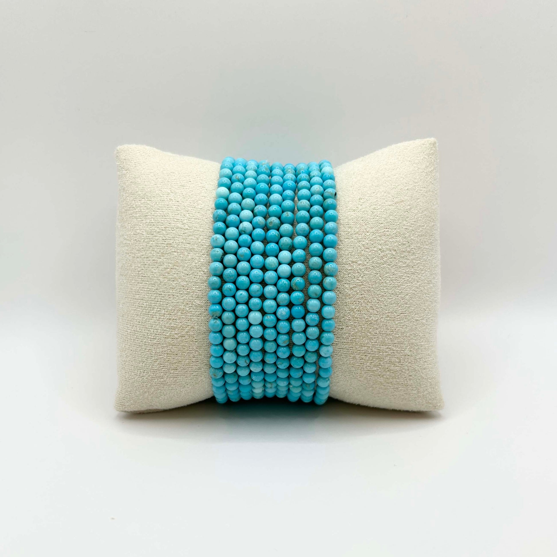 Affordable gemstone bracelet stack in vibrant turquoise – featuring smooth round beads perfectly aligned on a soft neutral cushion, ideal for creating a playful yet elegant wrist stack.