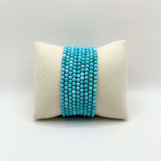 Affordable gemstone bracelet stack in vibrant turquoise – featuring smooth round beads perfectly aligned on a soft neutral cushion, ideal for creating a playful yet elegant wrist stack.