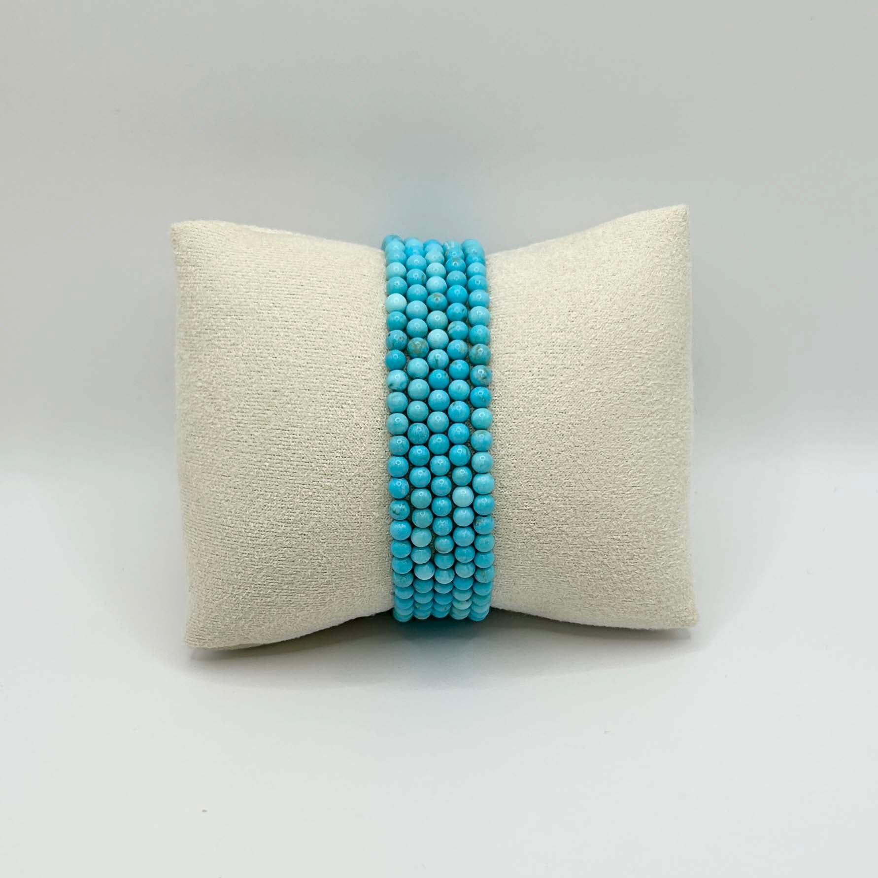 Affordable stack of turquoise Aurora bracelets displayed on a neutral cushion – elegant and minimalist gemstone jewellery perfect for layering or gifting.