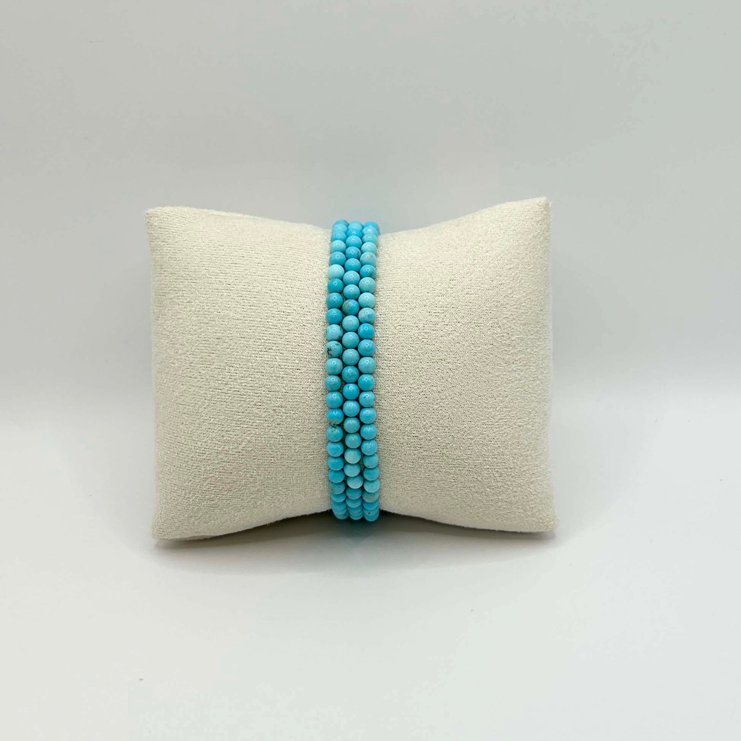 Affordable trio of vibrant turquoise gemstone bracelets from the Aurora collection, neatly displayed on a cream cushion – minimalist and colourful stacking jewellery.