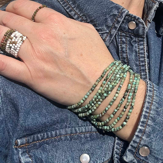 Stacked white and green African turquoise bracelets with Aurora white turquoise rings, styled with denim – affordable natural gemstone jewellery for everyday layering.