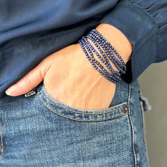 Multiple lapis lazuli beaded bracelets styled on wrist with denim outfit – deep blue gemstone jewellery, casual chic accessory for layering.