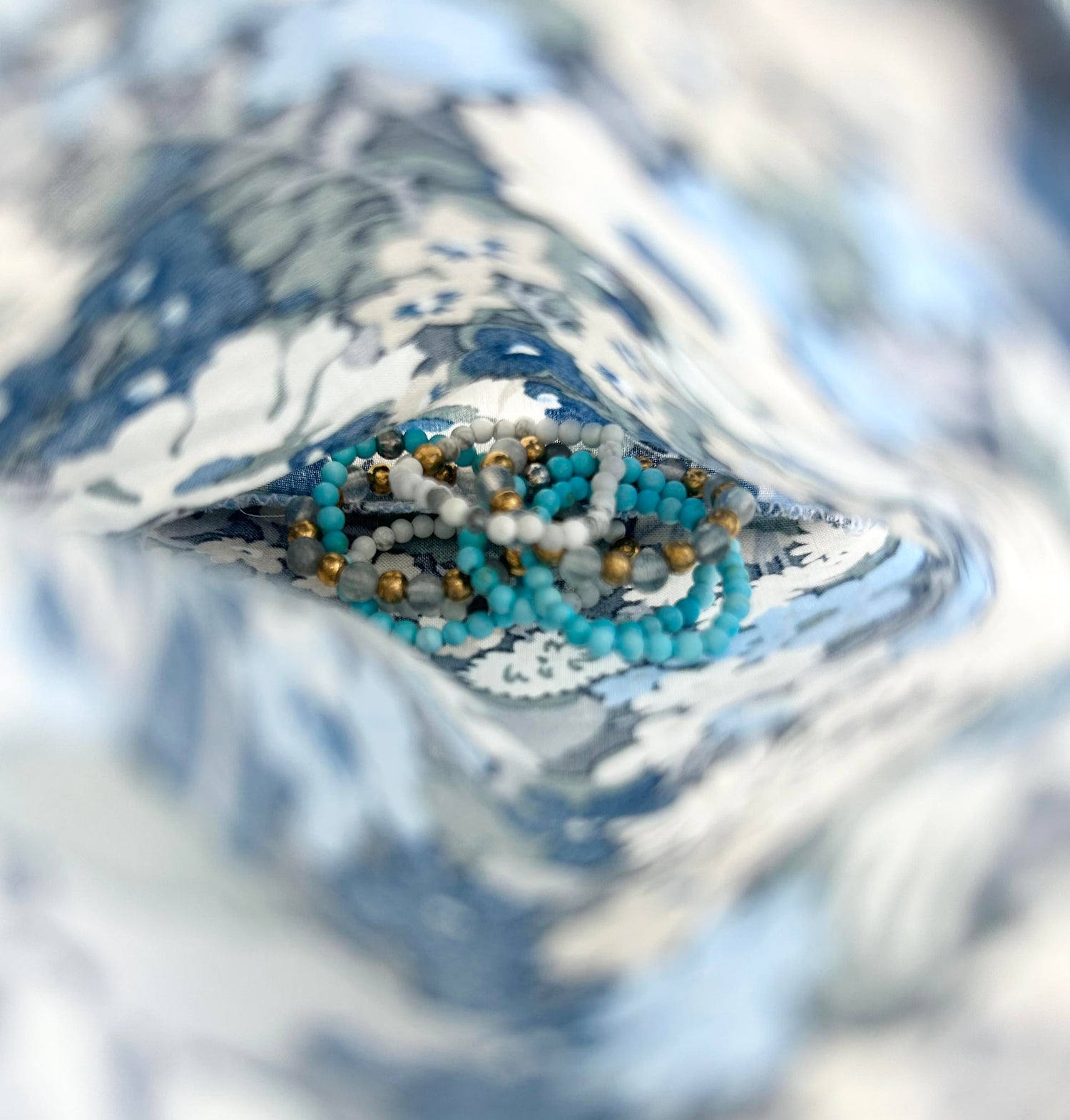 Affordable turquoise and white stackable rings by Leopoldine, styled inside a Liberty of London fabric pouch for a soft jewellery care moment.