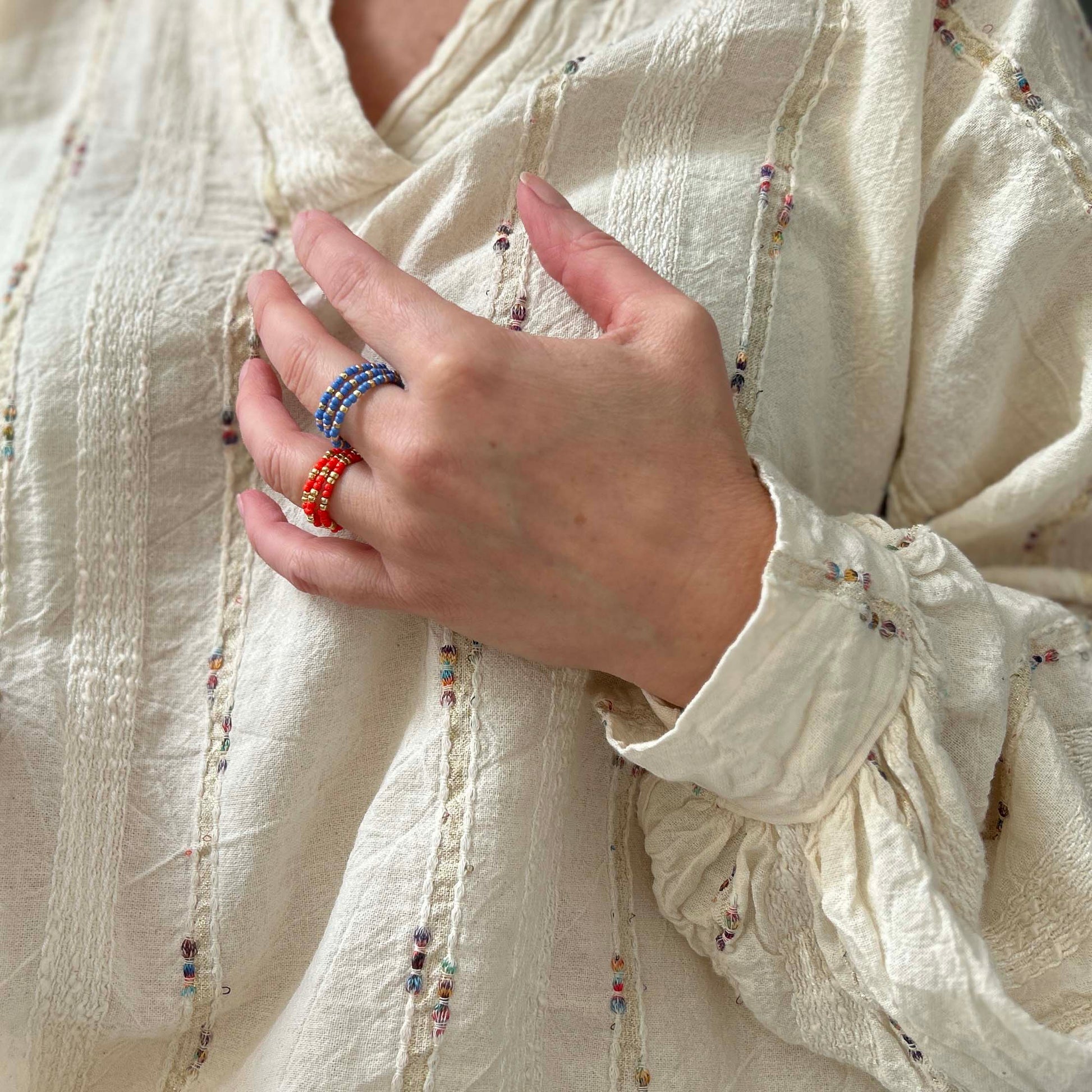 Set of three affordable Leopoldine Confettis rings in vibrant red and blue glass beads with gold accents, styled for a bold stacked look.