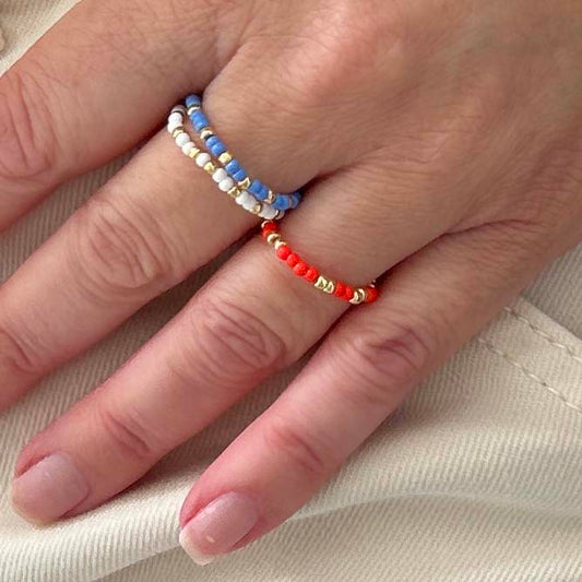 Close-up of Leopoldine Confettis rings in red, blue and white glass beads with gold accents — colourful stacked set sold as a trio in the UK.
