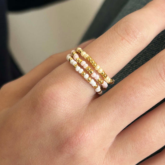 Close-up of Leopoldine Confettis trio ring set featuring cream, white, and pale pink glass beads with gold accents — elegant stackable rings for UK jewellery lovers.