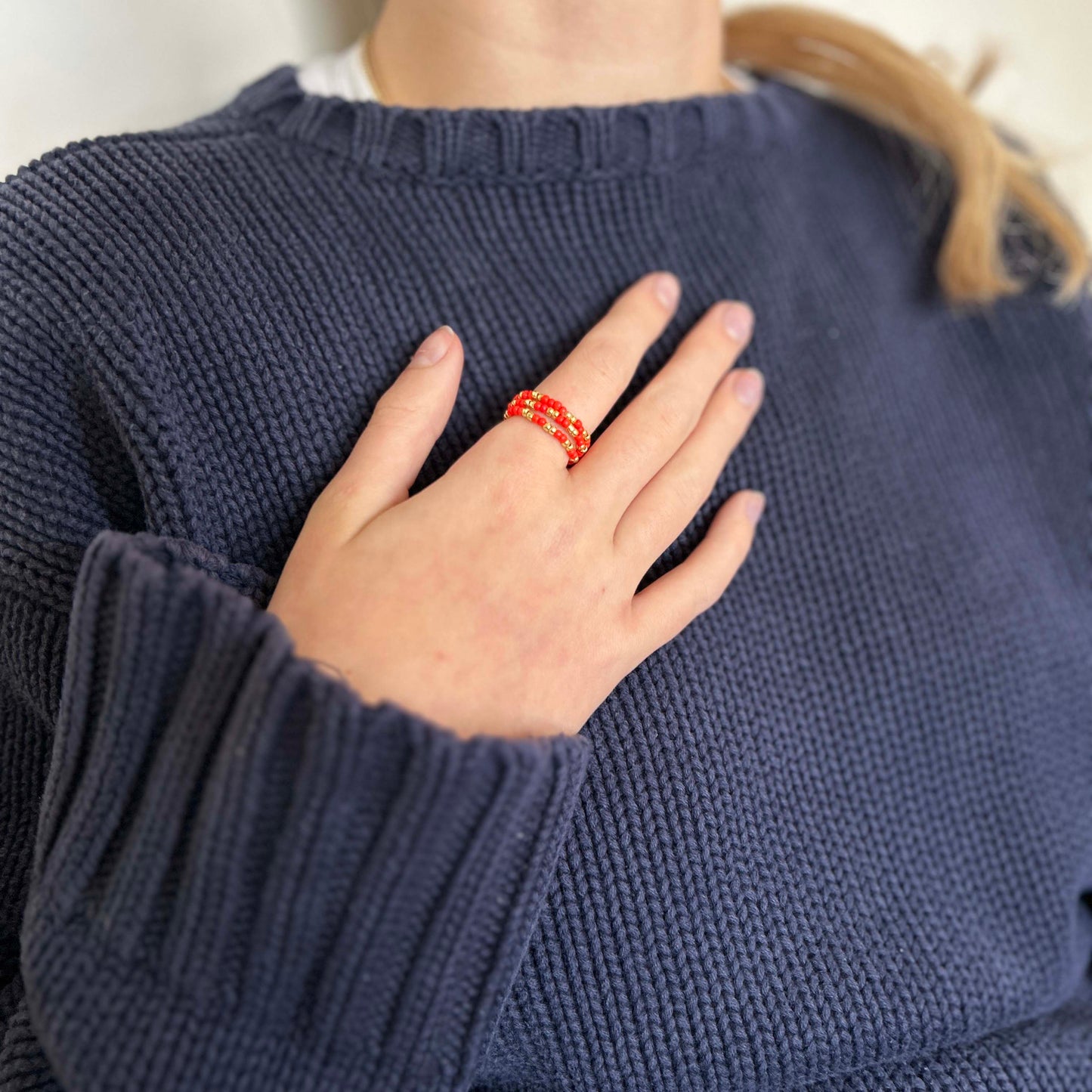 Woman wearing stackable Leopoldine Confettis rings in bold red glass beads and gold accents — vibrant statement jewellery for trendy UK style lovers.