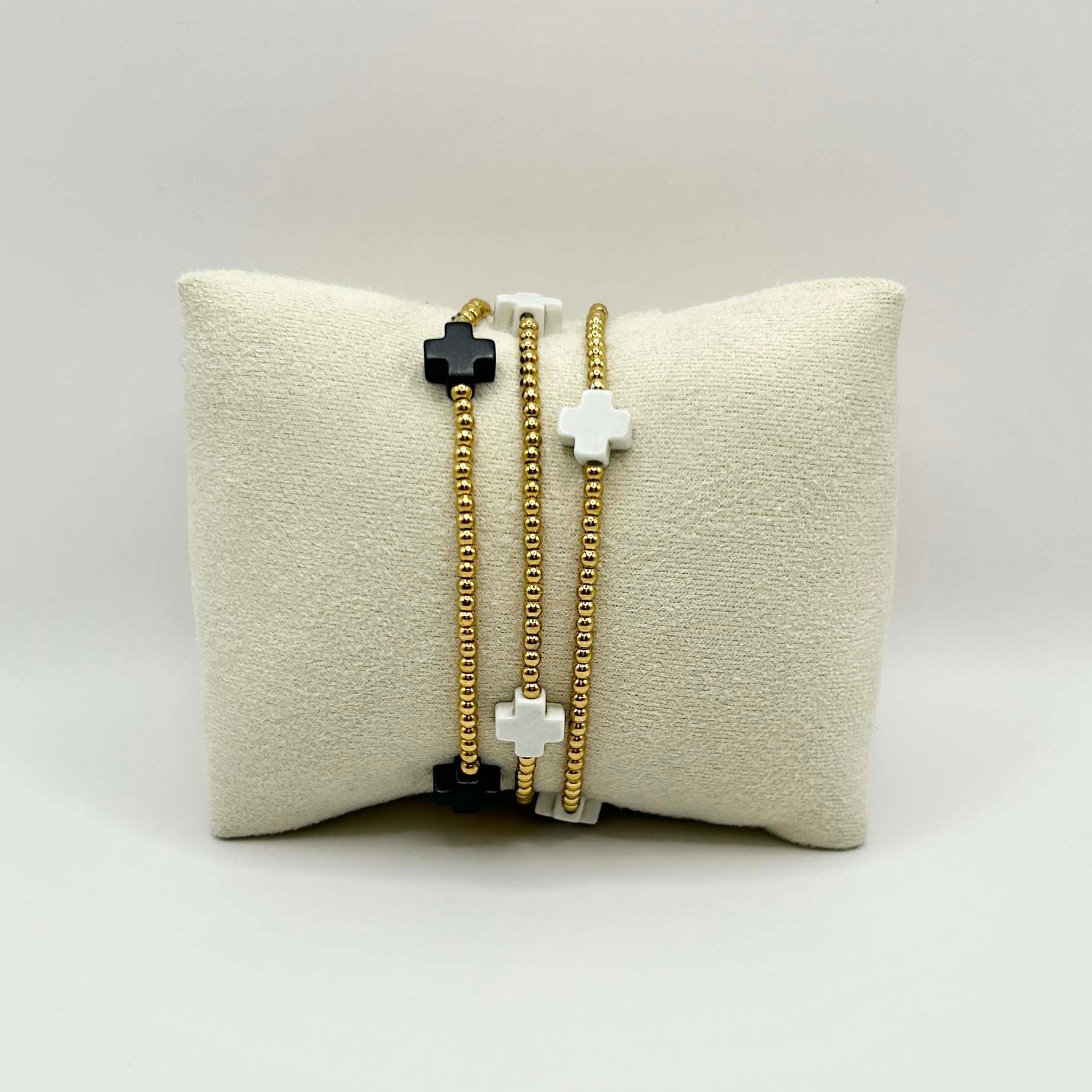 Minimalist trio of Divine cross bracelets in black, white and gold – elegant stacking jewellery in the UK, ideal for gifting or everyday layering.