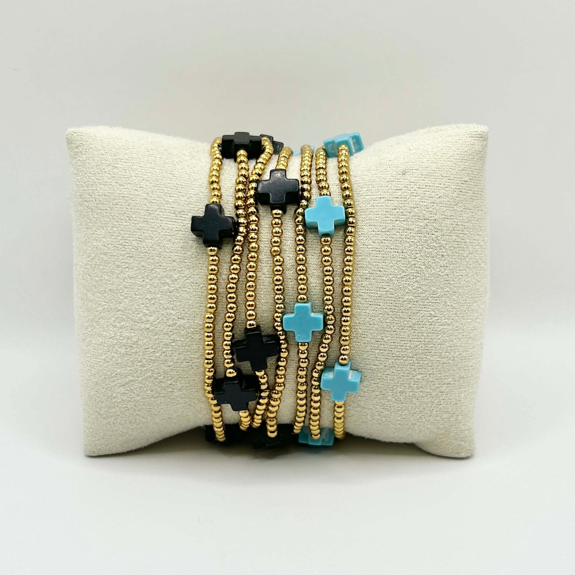 Affordable stacking bracelet set featuring turquoise and black cross charms on gold beaded strands – stylish UK jewellery perfect for layering, gifting or adding a pop of contrast to your everyday look.