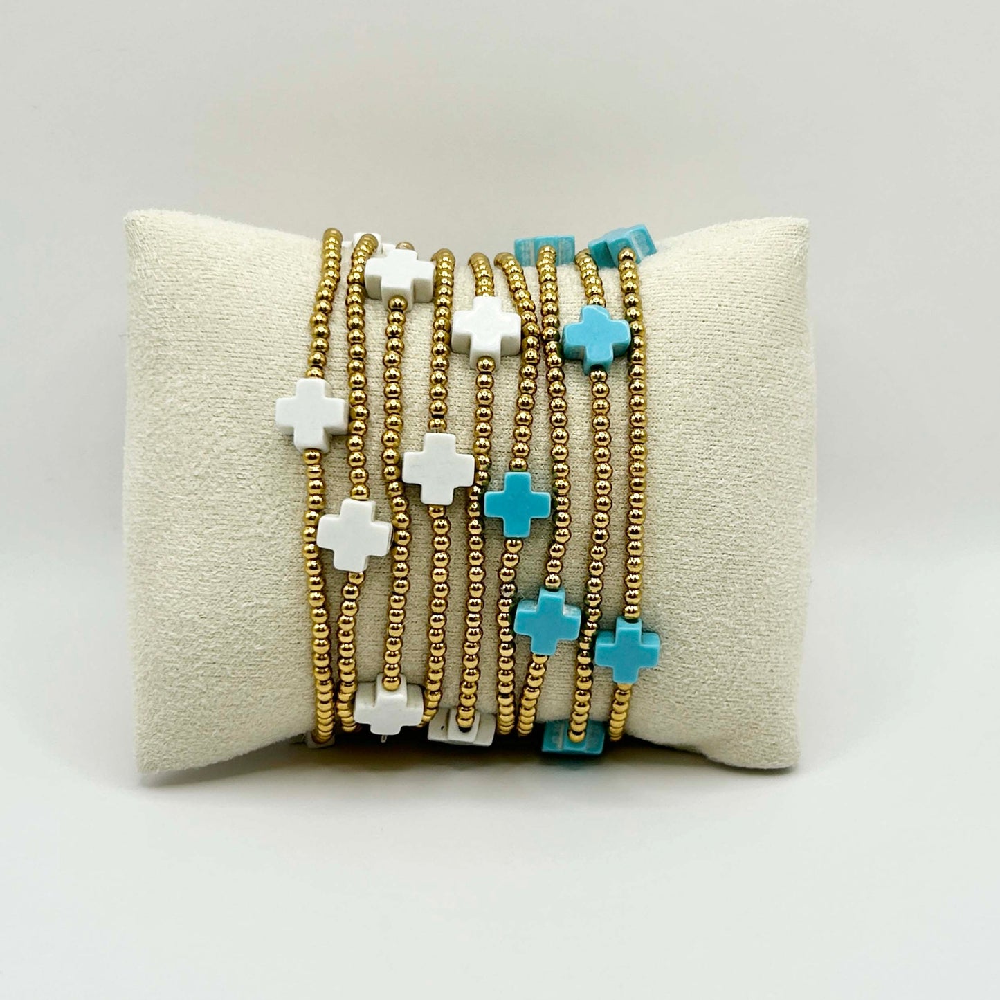 Stack of affordable gold beaded cross bracelets in turquoise and white – a unique, stylish jewellery combo from Leopoldine, perfect for layering and gifting in the UK.