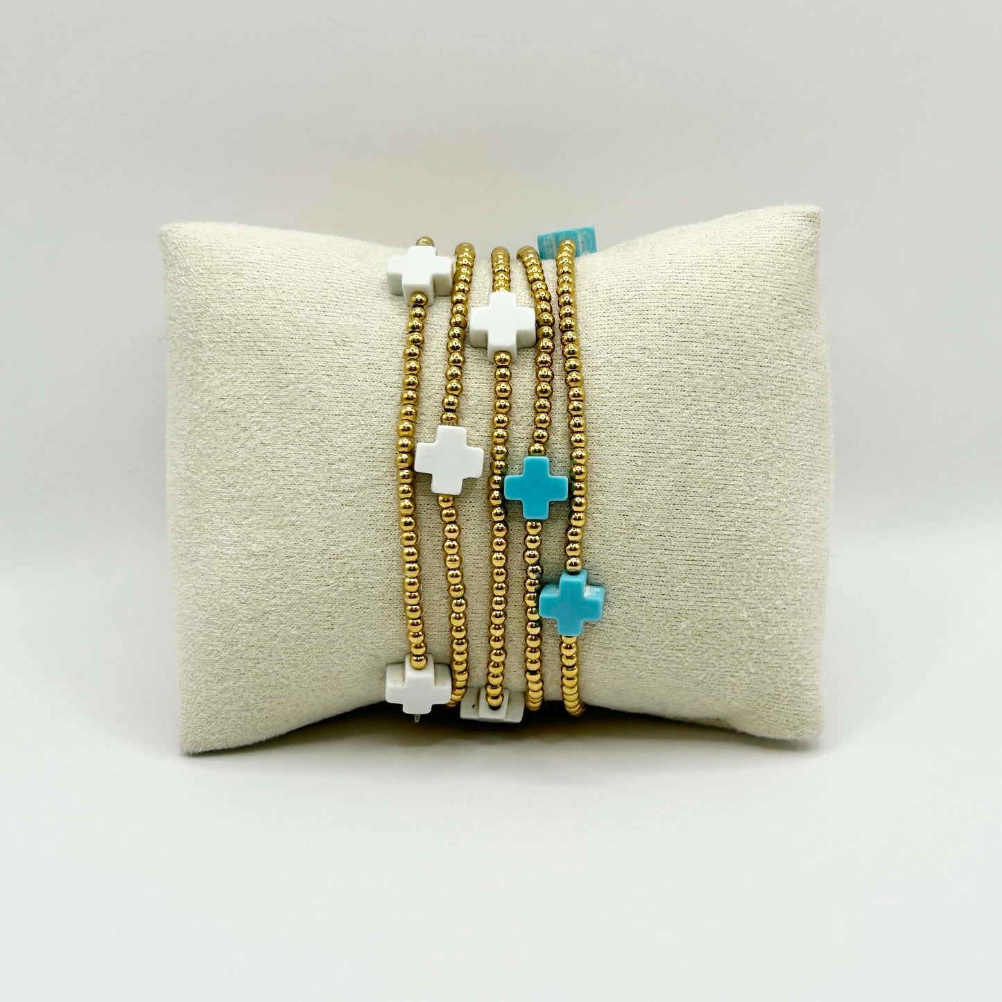 Affordable gold beaded bracelet stack featuring white and turquoise cross beads – a minimalist jewellery set from Leopoldine designed to layer effortlessly and elevate everyday looks in the UK.