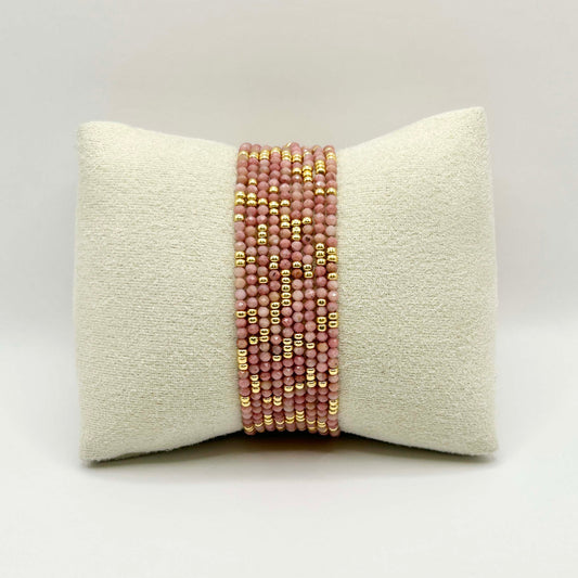 Close-up of the Leopoldine Selene bracelet in soft pink beads with golden accents, elegantly displayed on a cream cushion – feminine, delicate and perfect for stacking.