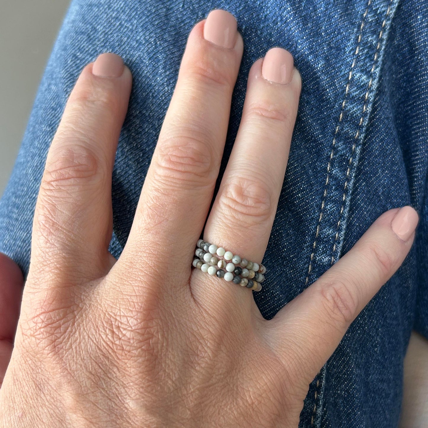 Hand wearing grey Picasso gemstone stackable rings, styled with denim for a laid-back jewellery look under £15 UK.